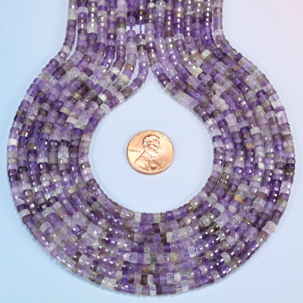 Amethyst faceted heishi disc strands formed into a teardrop loop around a US penny for scale