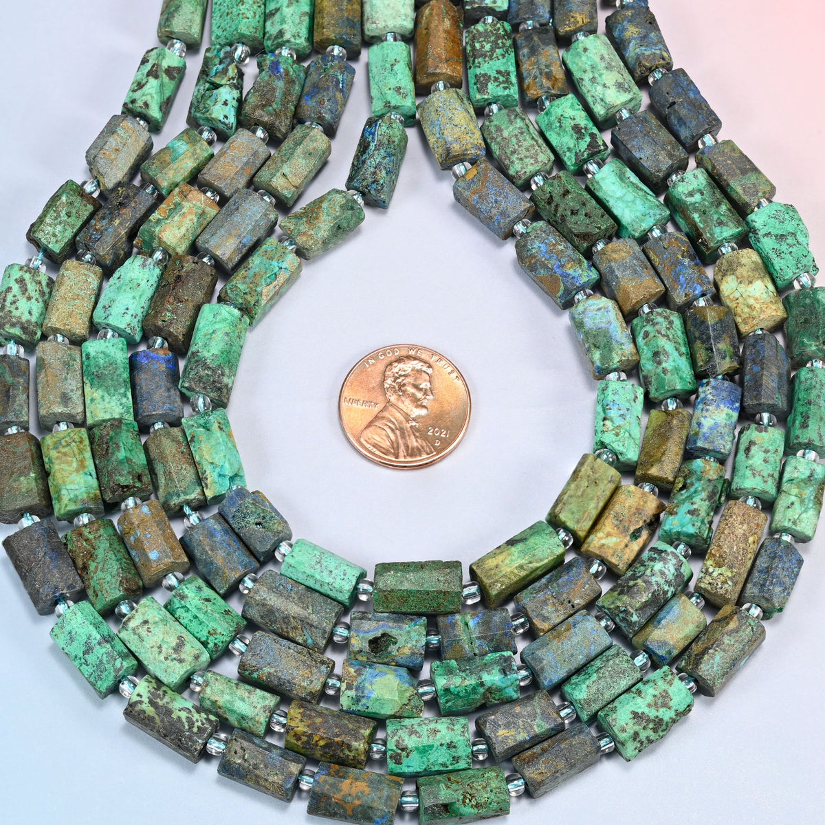 Azurite chrysocolla faceted tube strands formed into a teardrop loop around a US penny for scale