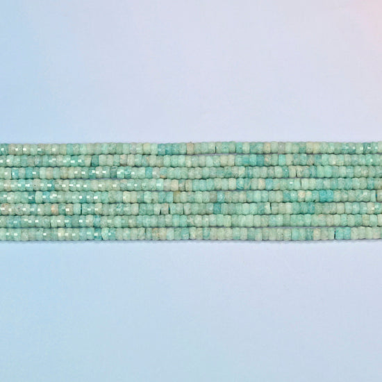 Several strands of green amazonite faceted heishi disc beads laid in straight rows