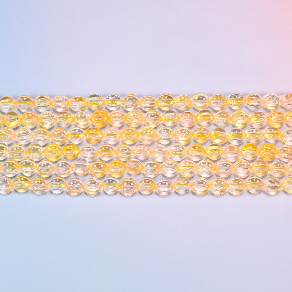 Close-up of 8mm yellow clear pumpkin glass beads in four horizontal rows, showing the carved melon ribs.