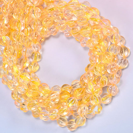 Yellow clear pumpkin glass beads coiled with the open center to one side, showing the fluted grooves end on.