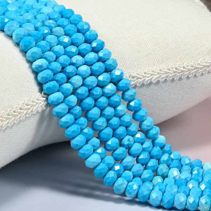 Dyed blue howlite faceted rondelle beads over a white cushion, even sky blue from bead to bead.