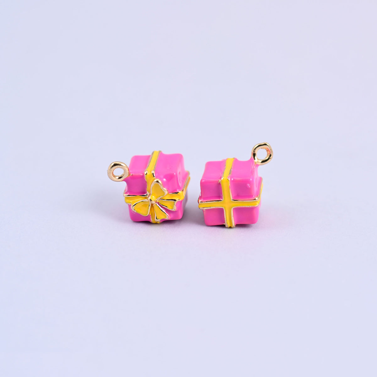 Two pink gift box charms with yellow enamel ribbon and bow.