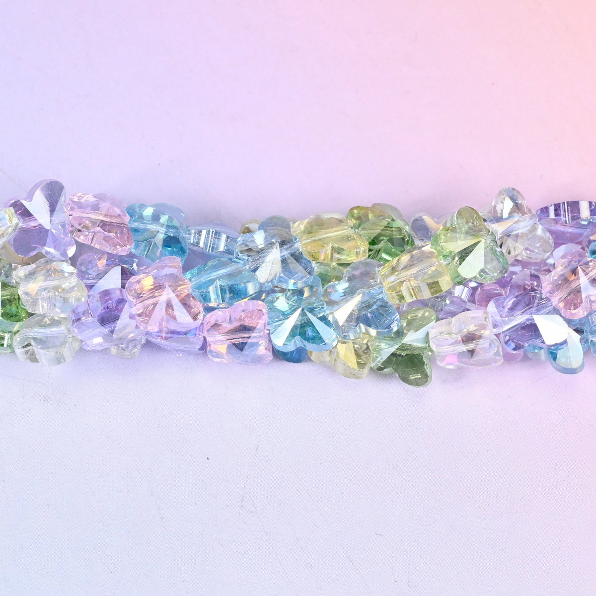 Small pressed-glass butterflies in clear pastel lilac, aqua, mint, lemon and pink, each finished with an iridescent coating that throws rainbow flashes off the wing facets.