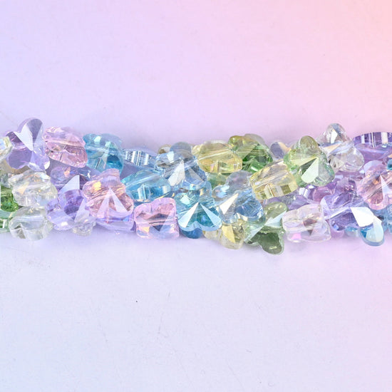 Small pressed-glass butterflies in clear pastel lilac, aqua, mint, lemon and pink, each finished with an iridescent coating that throws rainbow flashes off the wing facets.