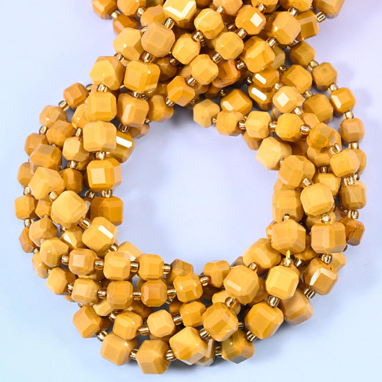 A warm opaque mustard running from pale honey to deep caramel, cut into small faceted cubes whose flat corners catch a soft matte shine.