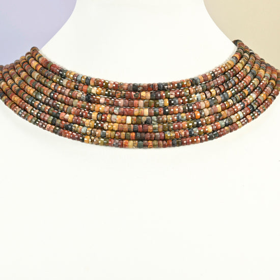 Red howlite faceted heishi disc strands arranged as a layered collar on a white display bust, red, green and tan beads across the neck