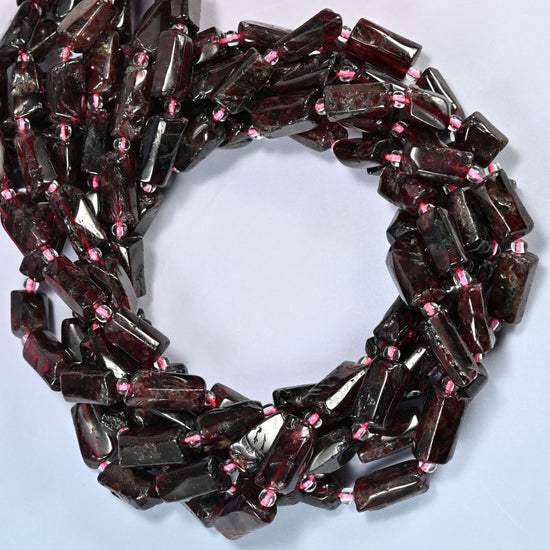Red garnet tube beads coiled into overlapping loops, whole strands of deep cherry red stone