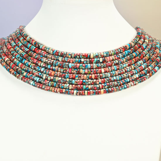 Dyed red blue sea sediment jasper heishi disc strands arranged as a layered collar on a white display bust