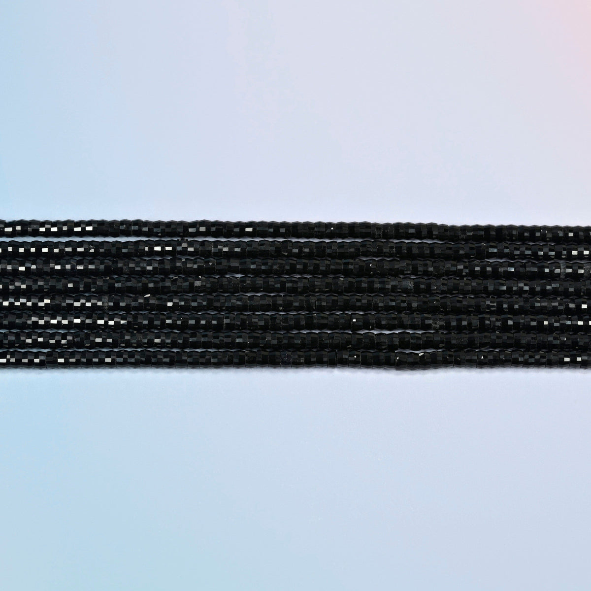 Several strands of black onyx faceted heishi disc beads laid in straight rows