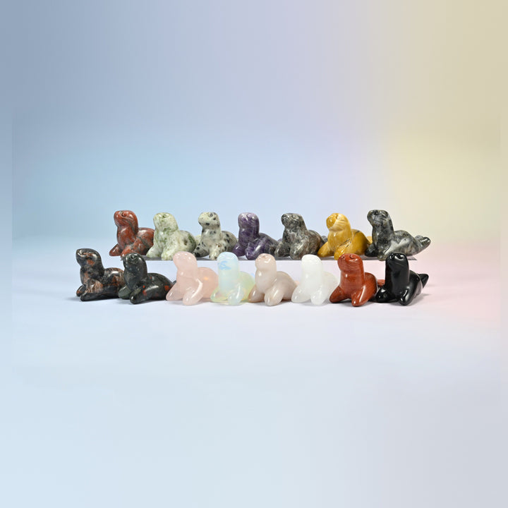 Group of 1.5 inch sea lion crystal carvings in natural stones including red jasper, rose quartz, amethyst, kiwi jasper, black obsidian, mookaite and opalite