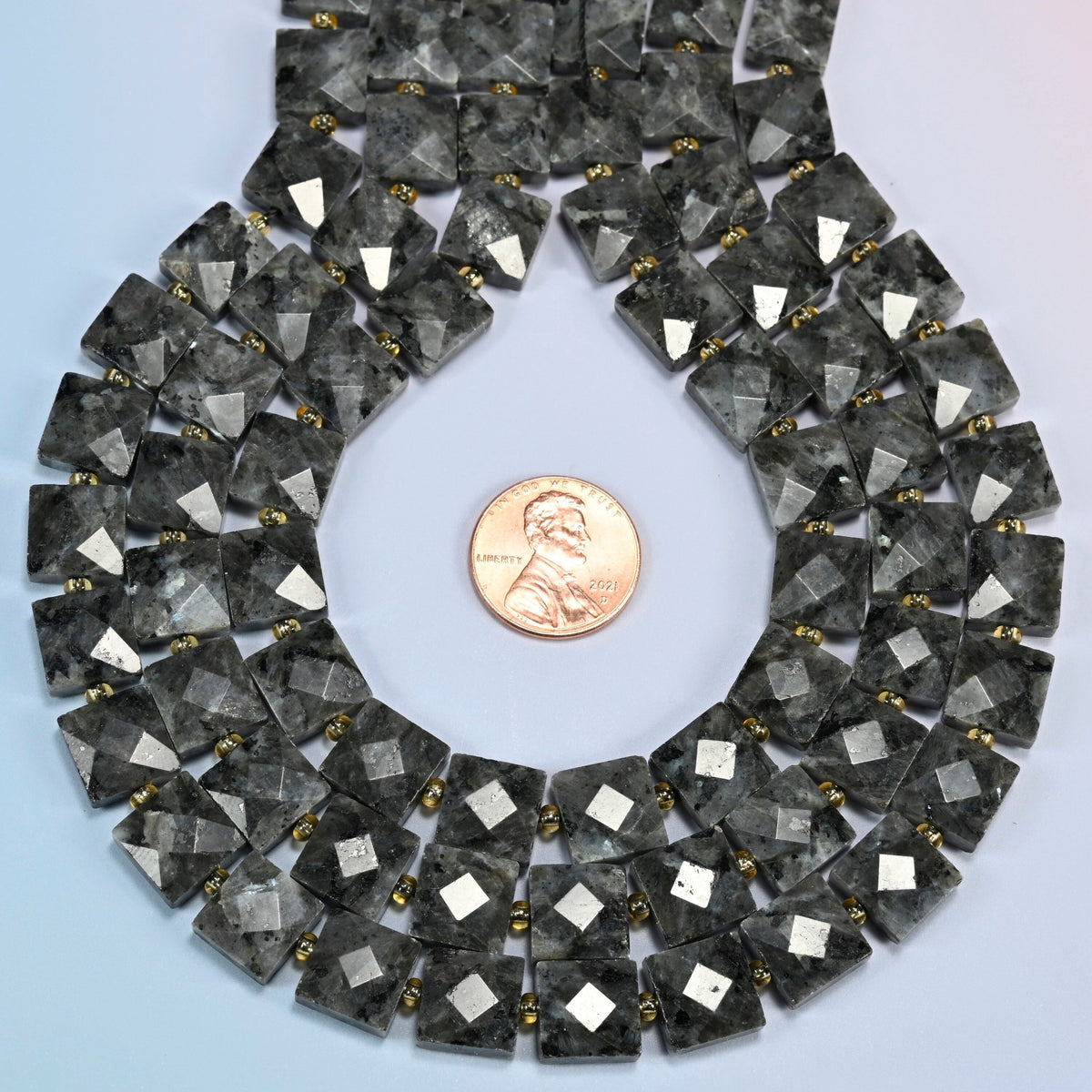 Natural black labradorite faceted flat square strands formed into a teardrop loop around a US penny for scale