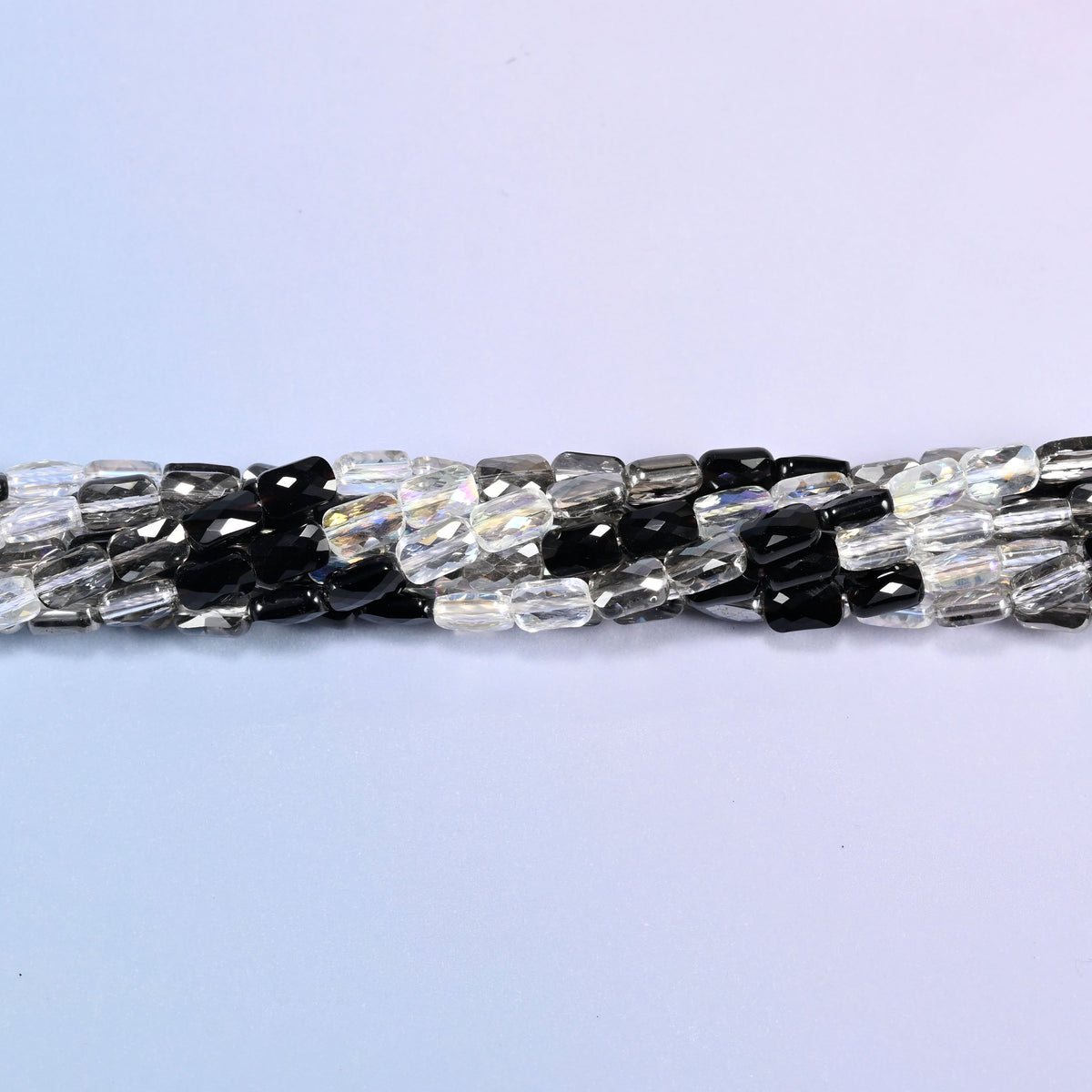 Black gray clear faceted rectangle glass beads twisted into a narrow rope across the frame.