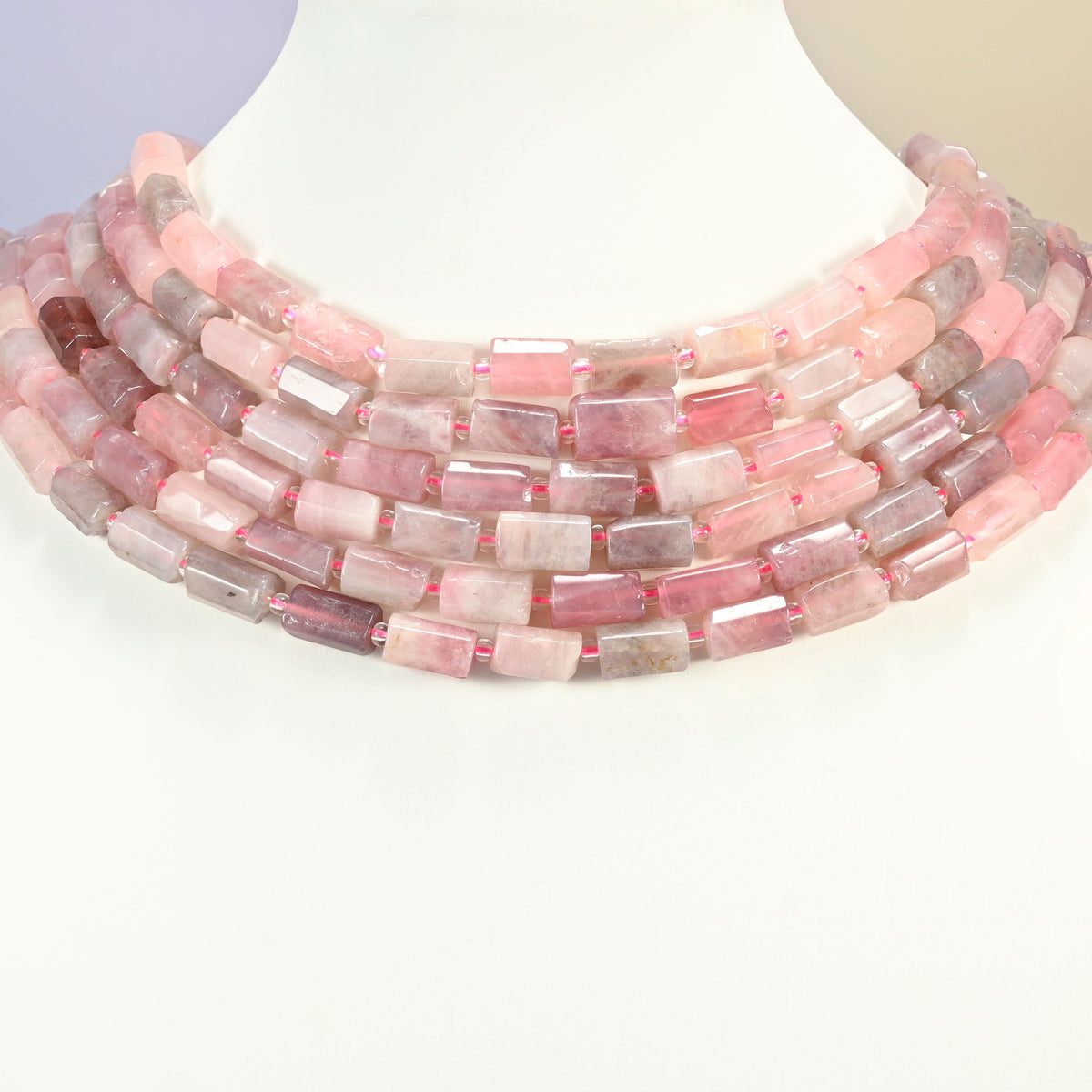Madagascar multi color rose quartz faceted tube beads layered as graduated collar rows on a white neck display bust.