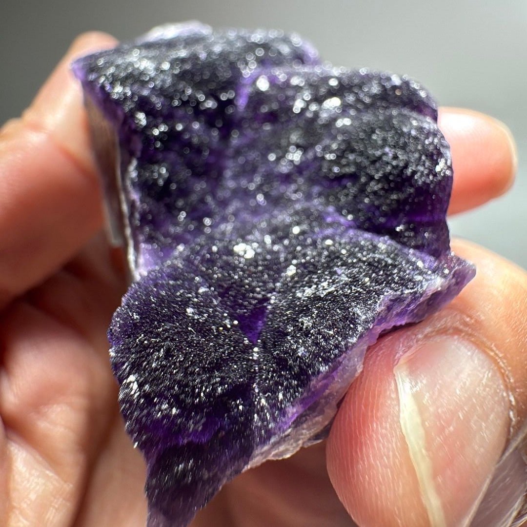 Dark purple fluorite mineral specimen with frosted quartz crust across the upper face.