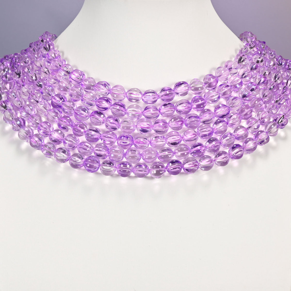 Clear purple pumpkin glass beads shown as layered strands on a white neck display form.