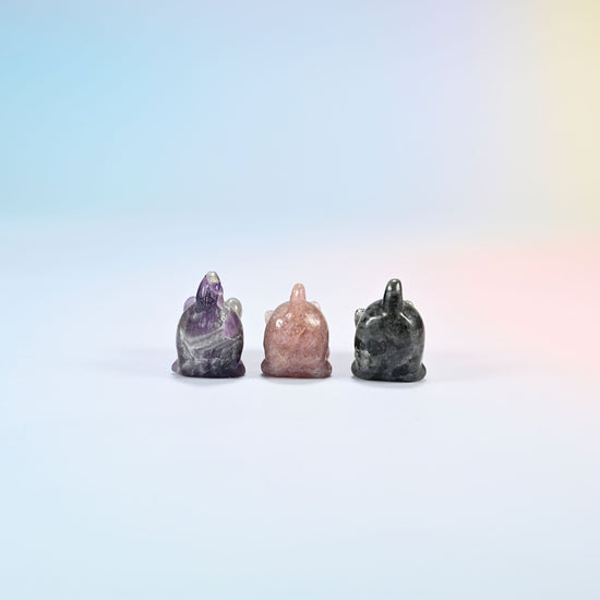 Back view of natural amethyst, strawberry quartz and black labradorite yoga cat carvings showing their raised tails