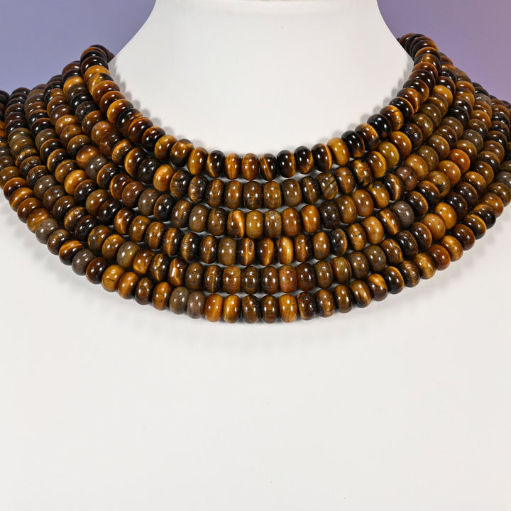 Multi-strand Tiger Eye necklace laid flat on a mannequin neck form against a lavender background.