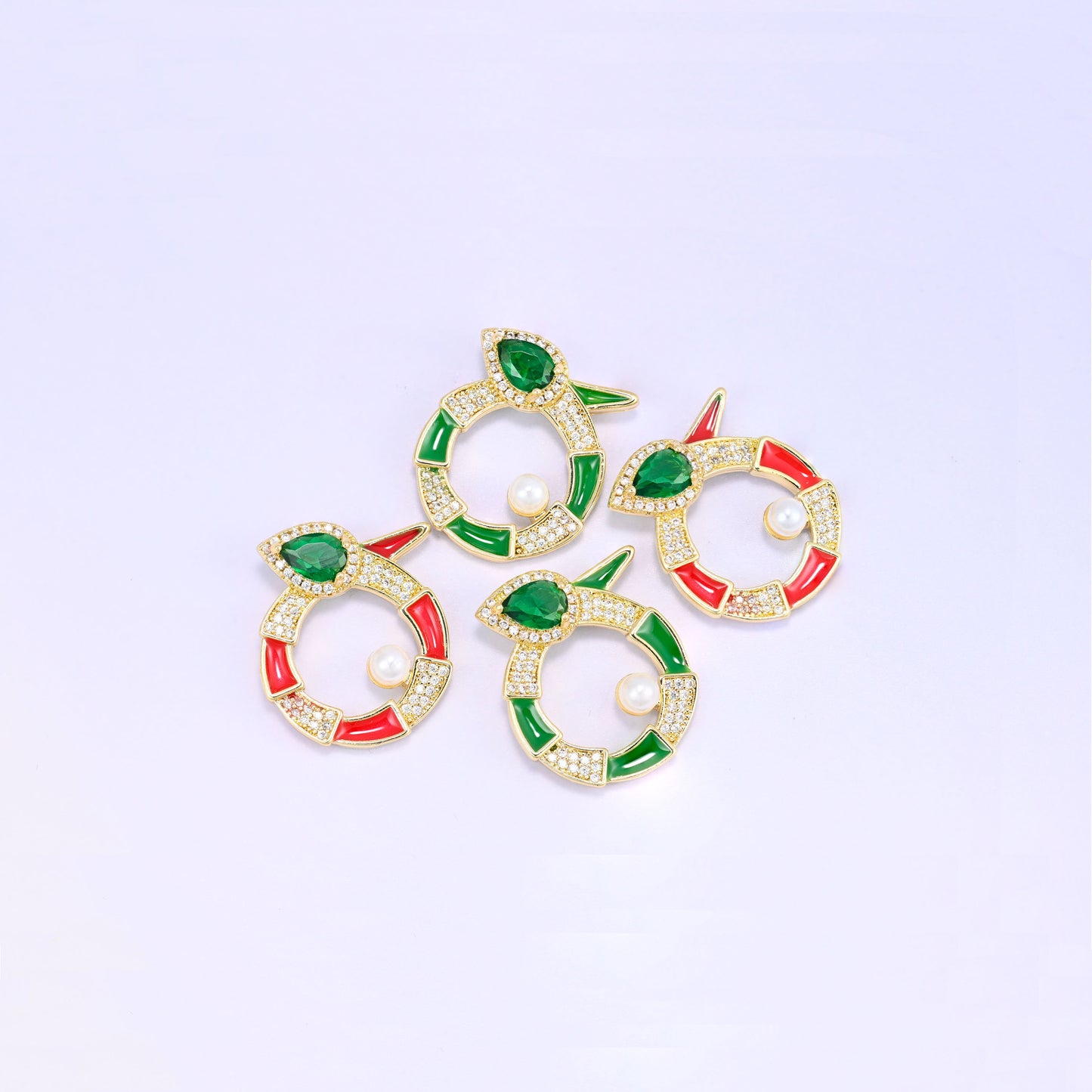 Four round snake charms grouped at an angle, two green and two red enamel pieces with pave zircon, pear cut green stones and pearl centres.