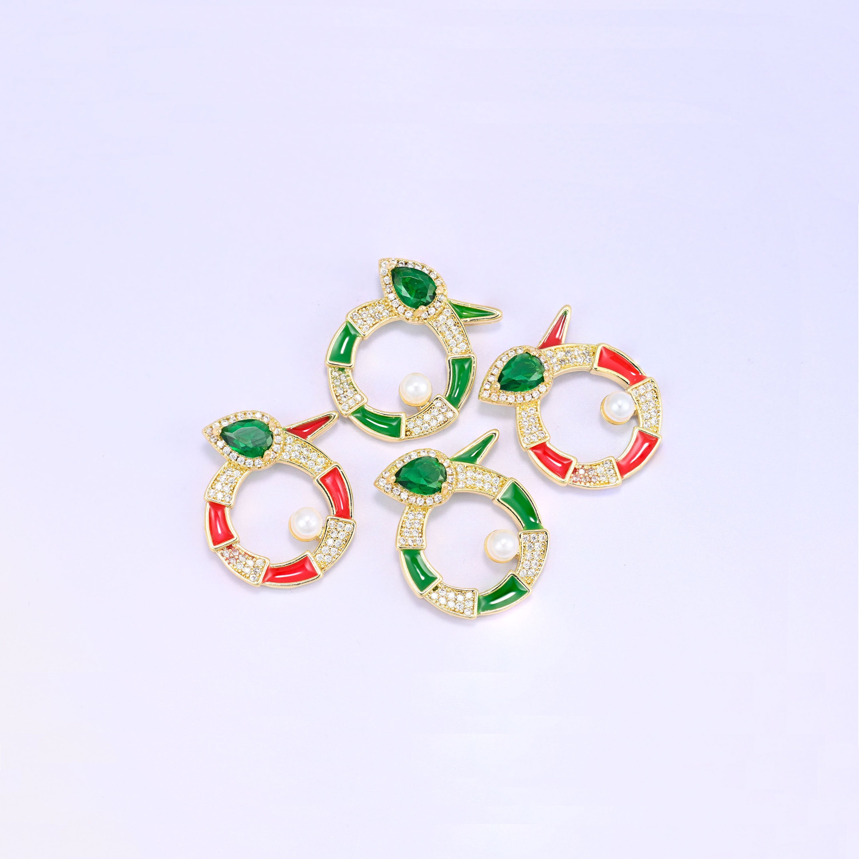 Four round snake charms grouped at an angle, two green and two red enamel pieces with pave zircon, pear cut green stones and pearl centres.
