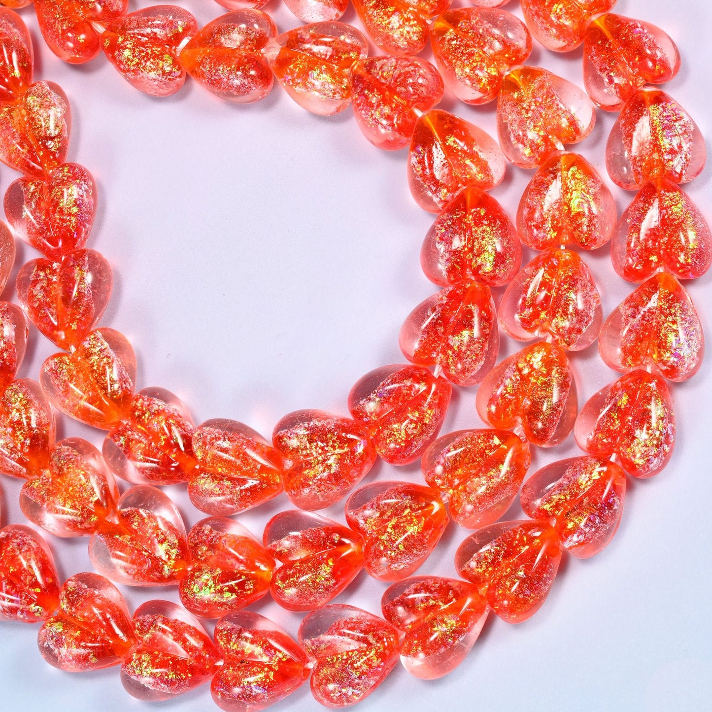 Warm coral-red glass heart beads with golden iridescent glitter