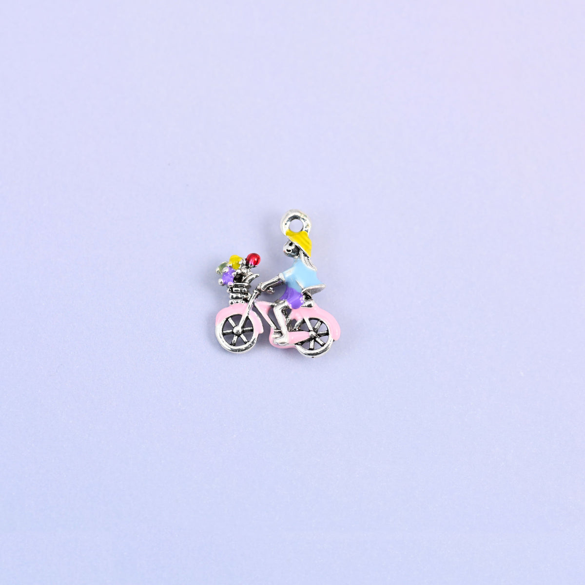 Bicycle charm with a yellow haired rider in a light blue top and a green flower basket on the front.