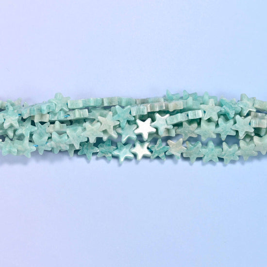 A chalky seafoam blue-green lightly mottled with white and the odd tan fleck, cut into small flat five-pointed stars whose matte-satin surface keeps the color soft rather than glassy.