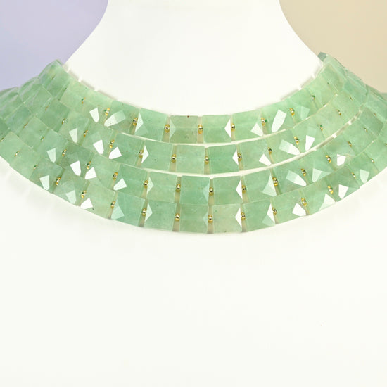 Natural green aventurine faceted flat square strands arranged as a layered collar on a white display bust, light green beads across the neck