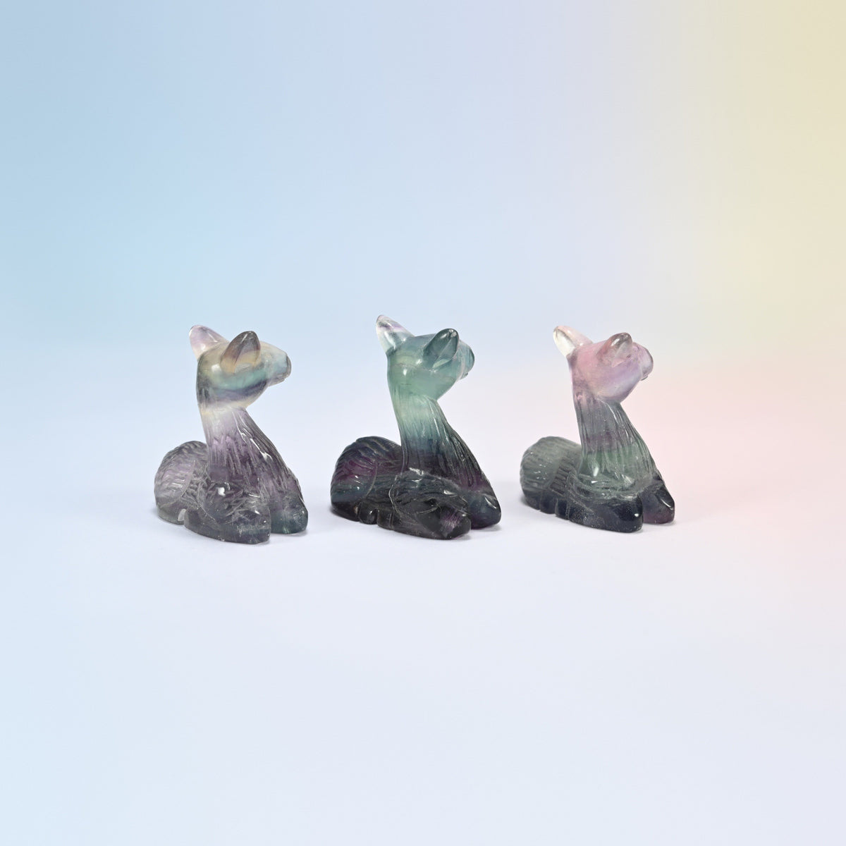 Side view of three rainbow fluorite deer showing the raised heads and pricked ears
