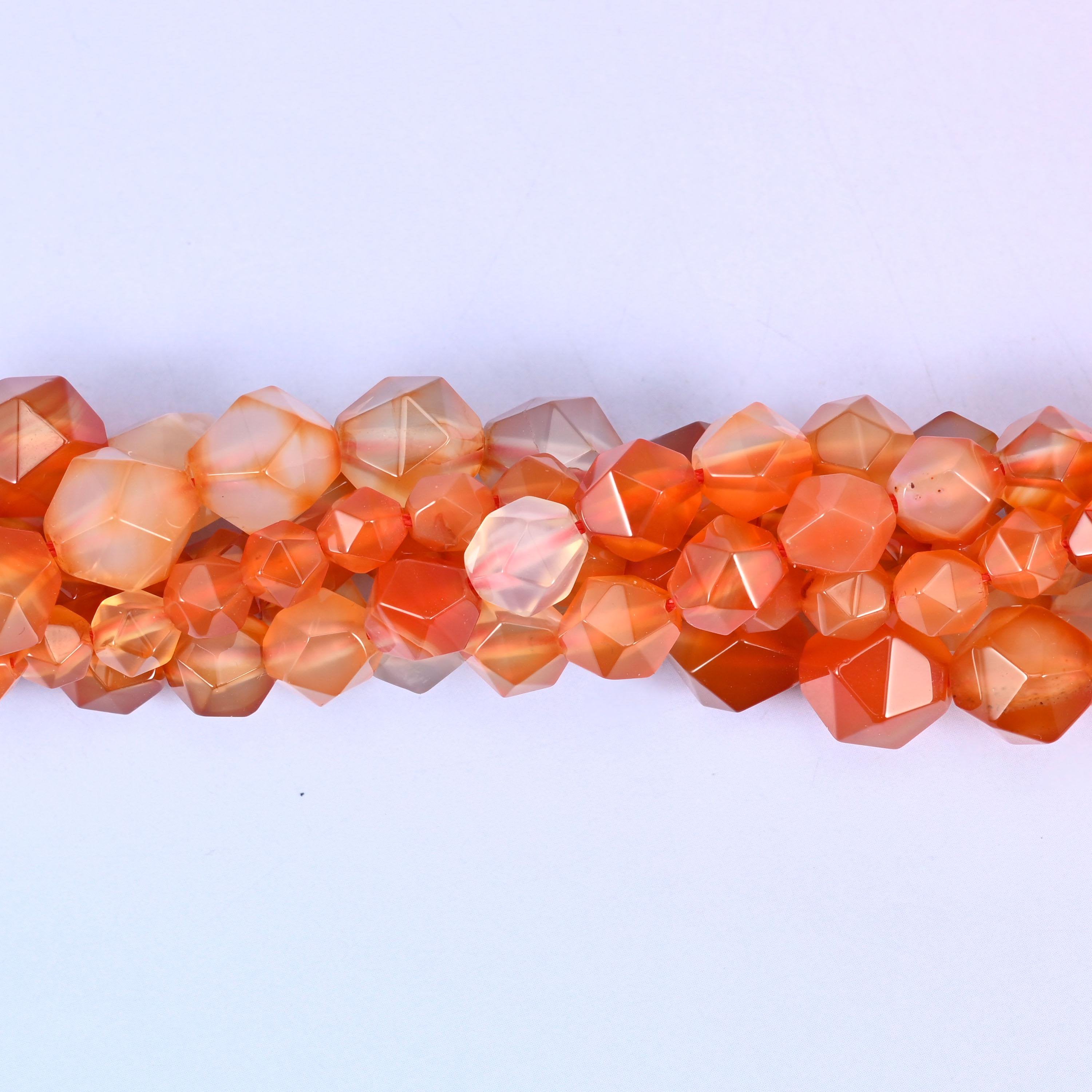 Orange Agate faceted beads close up in a single row, flat triangular star cut planes over orange and cream banding