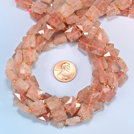 Natural strawberry quartz faceted flat square beads 10x10mm coiled in a loop around a US penny for scale, close-up of the faceted flat square shape
