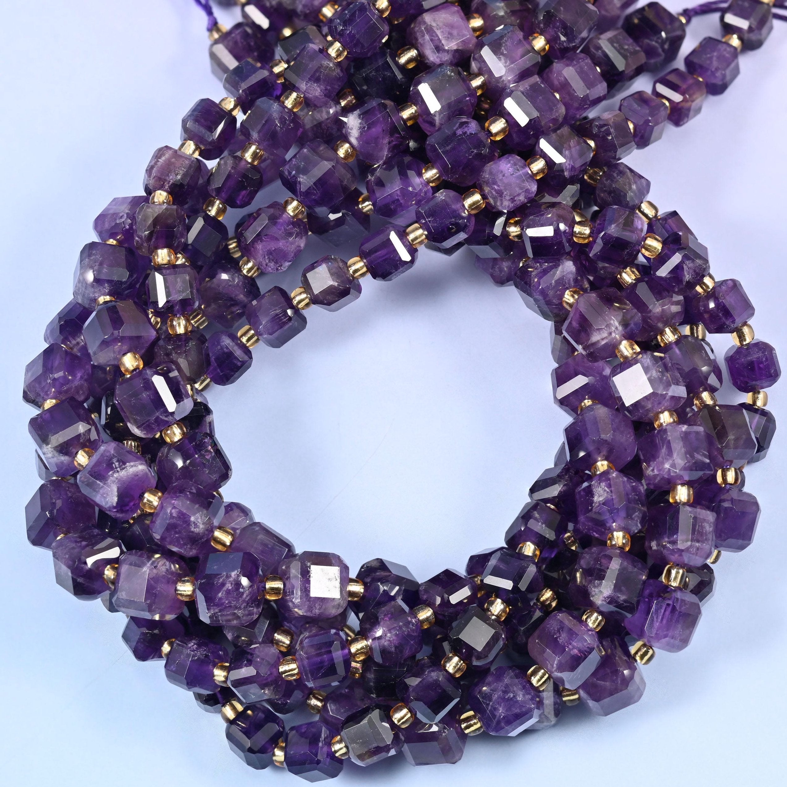 Deep grape purple cubes veined with paler lilac and milky white zoning, faceted at the corners so each flat face throws its own highlight.