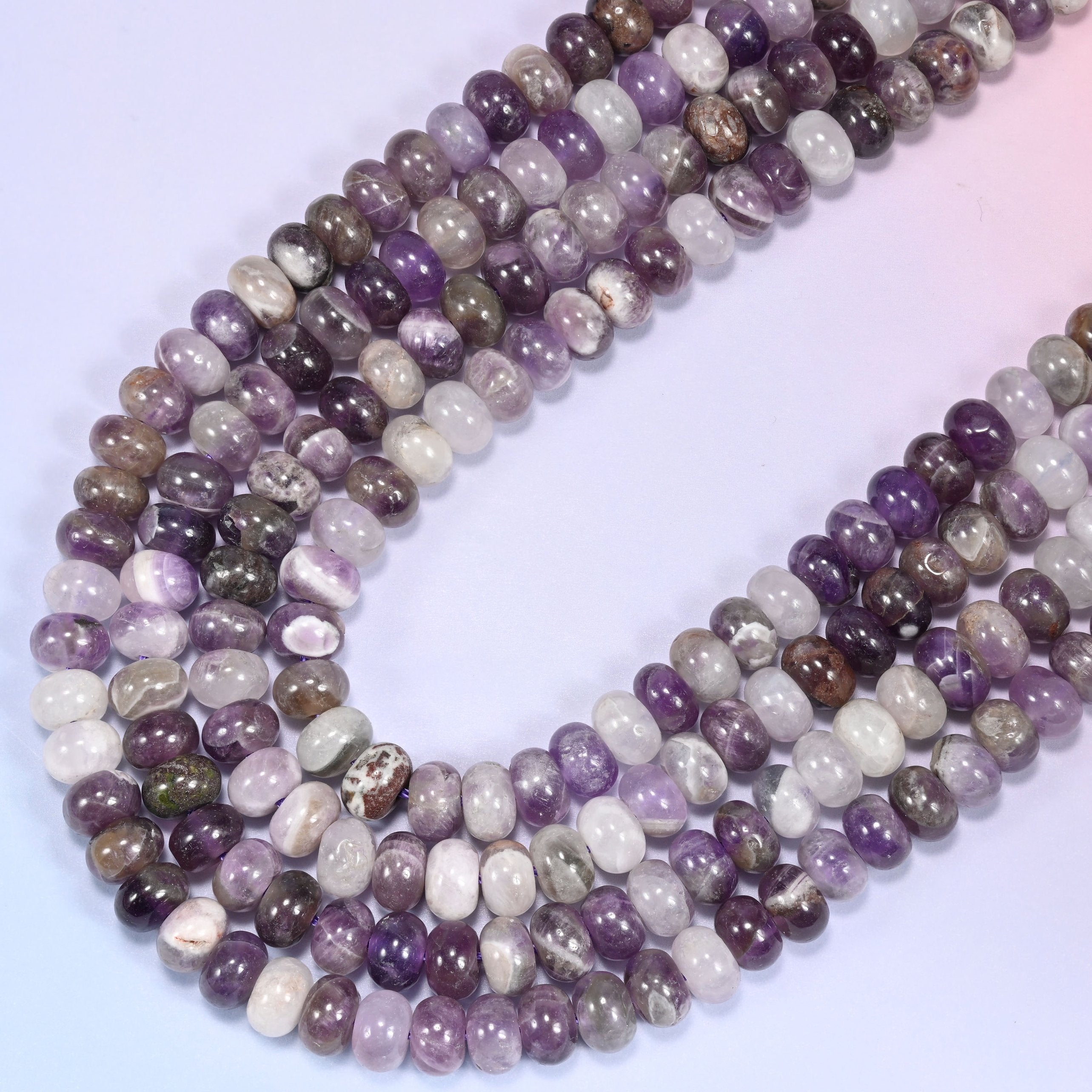 Close-up of Amethyst rondelle beads coiled in a circular arrangement on a lavender background.