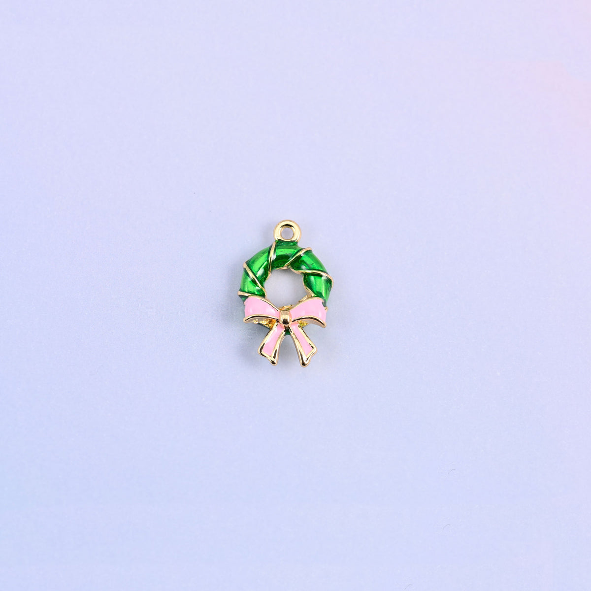 Green enamel wreath charm with a light pink bow, the ring twisted like a wound garland with gold banding between the turns.