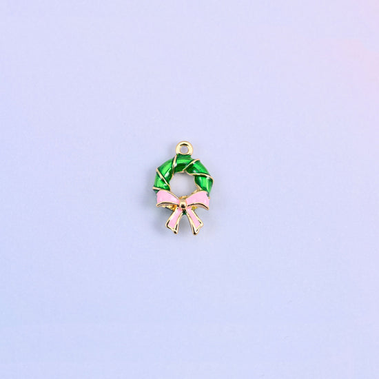 Green enamel wreath charm with a light pink bow, the ring twisted like a wound garland with gold banding between the turns.