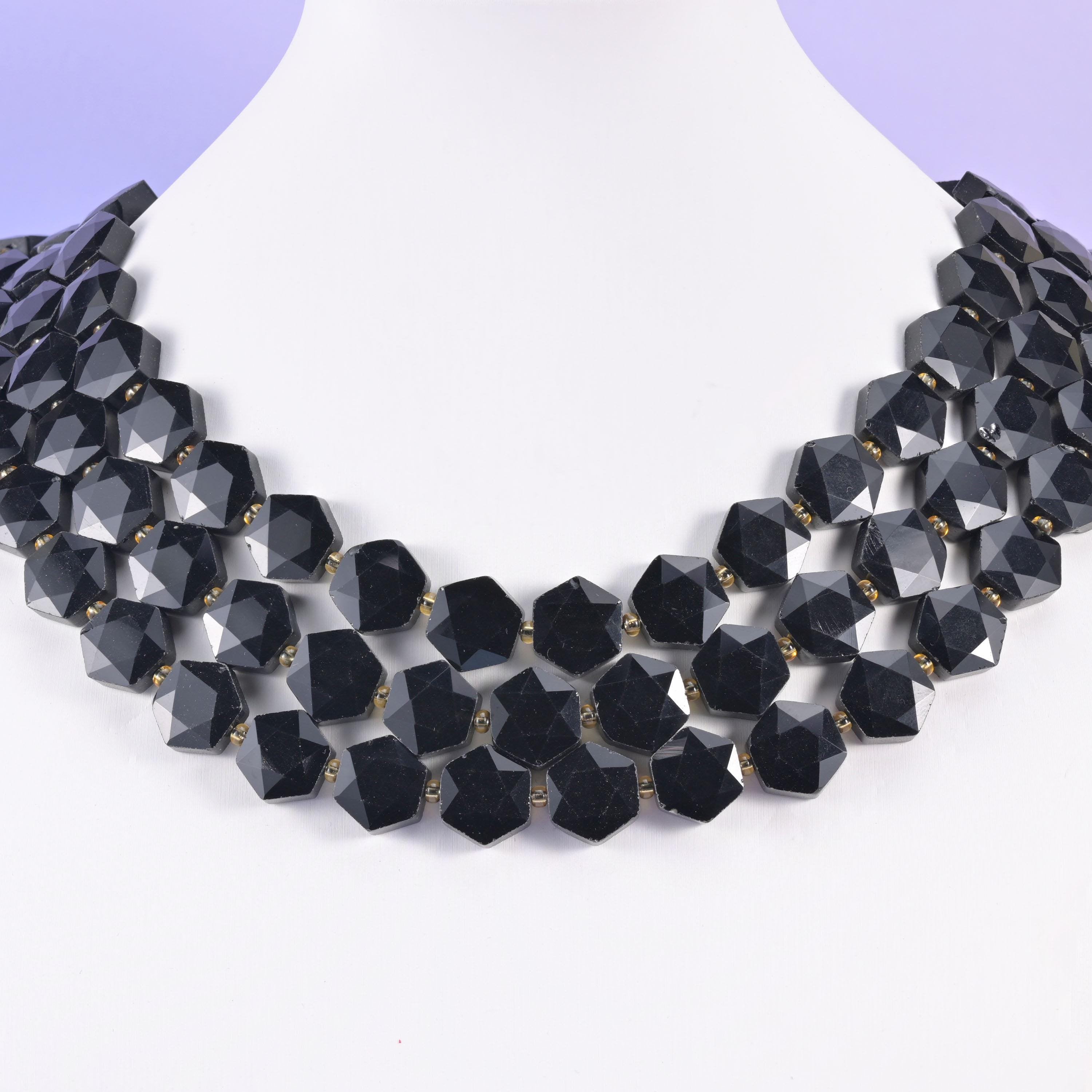 Faceted obsidian hexagons layered on a display bust, forming a dark geometric collar
