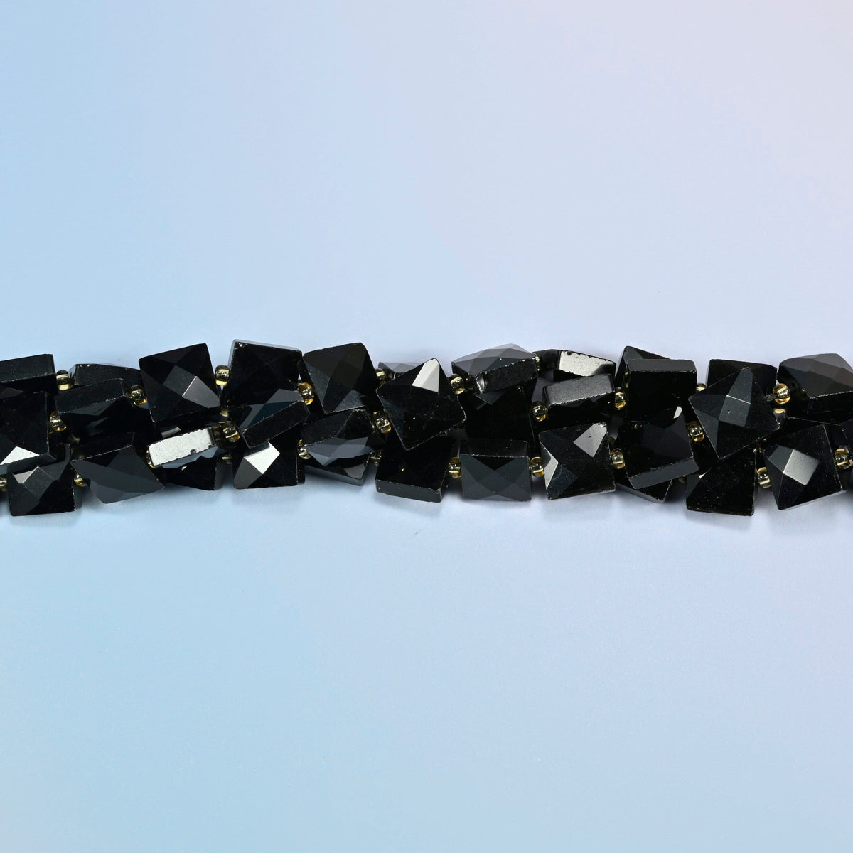 Strands of natural black onyx faceted flat square beads twisted together in a horizontal row