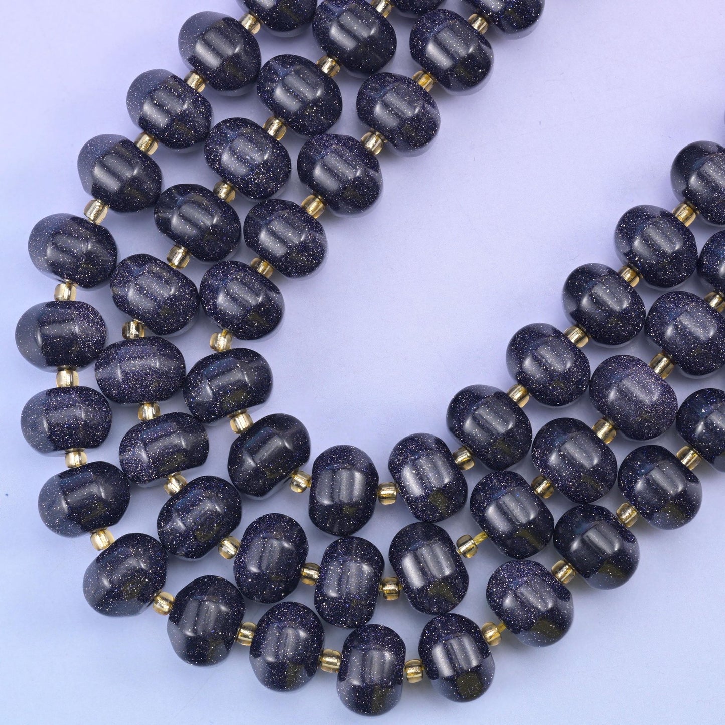 Blue Sandstone pumpkin rondelles sweeping into a V on a lilac background