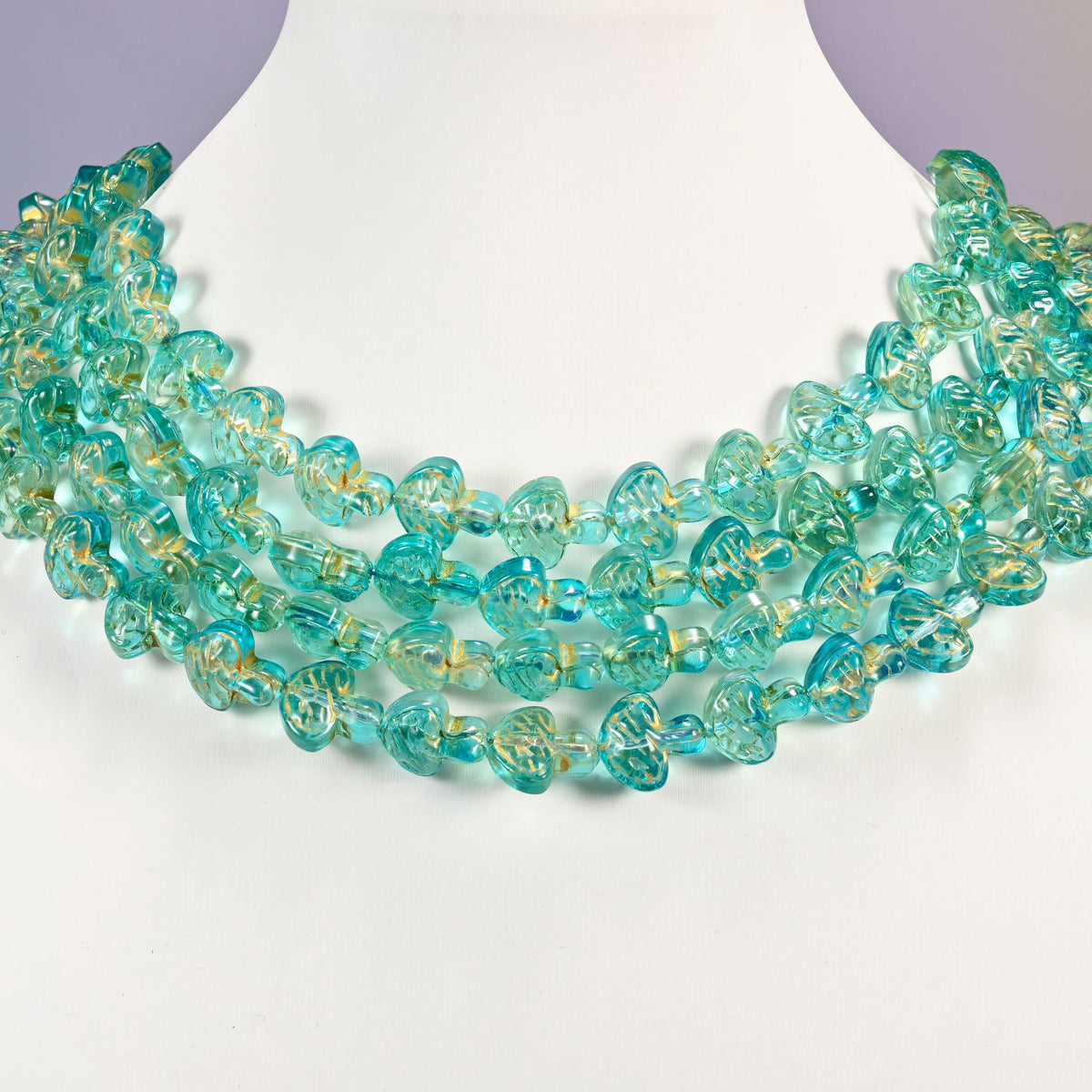 Aqua gold flat mushroom glass beads arranged as a layered collar, the 15 inch strands curving in even rows.