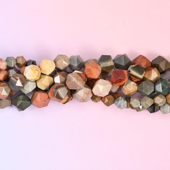 Tan, rust, grey and cream banded through every bead, then cut into a faceted diamond star so the pattern breaks into small bright planes — earthy desert colour with real sparkle to it.