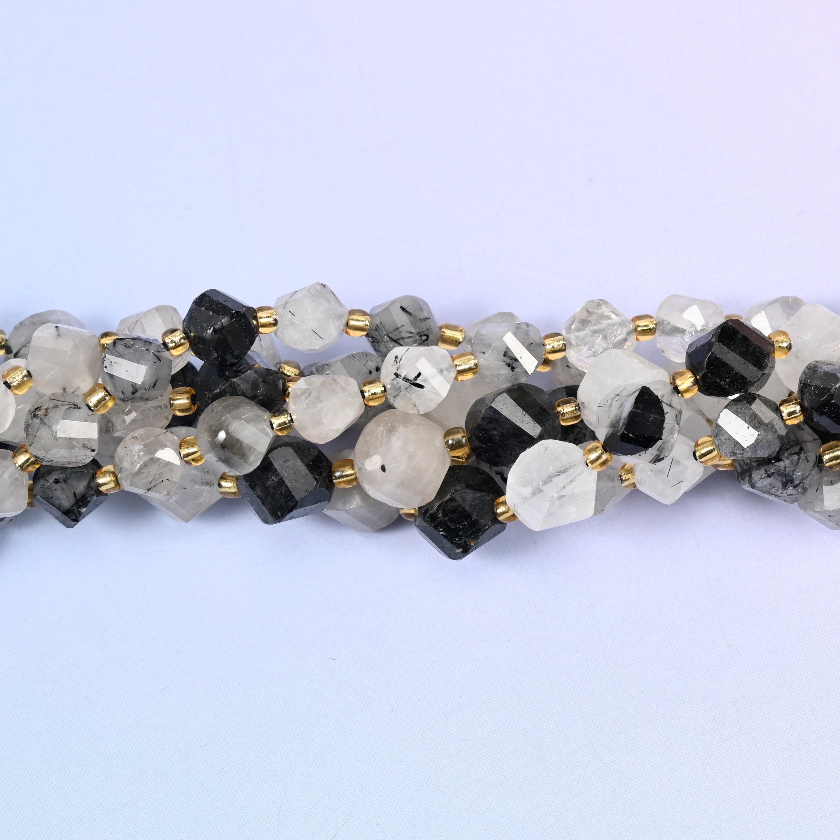 Clear to snowy white quartz shot through with jet-black tourmaline needles, running from beads with only a few fine dark threads to beads that are almost solid black