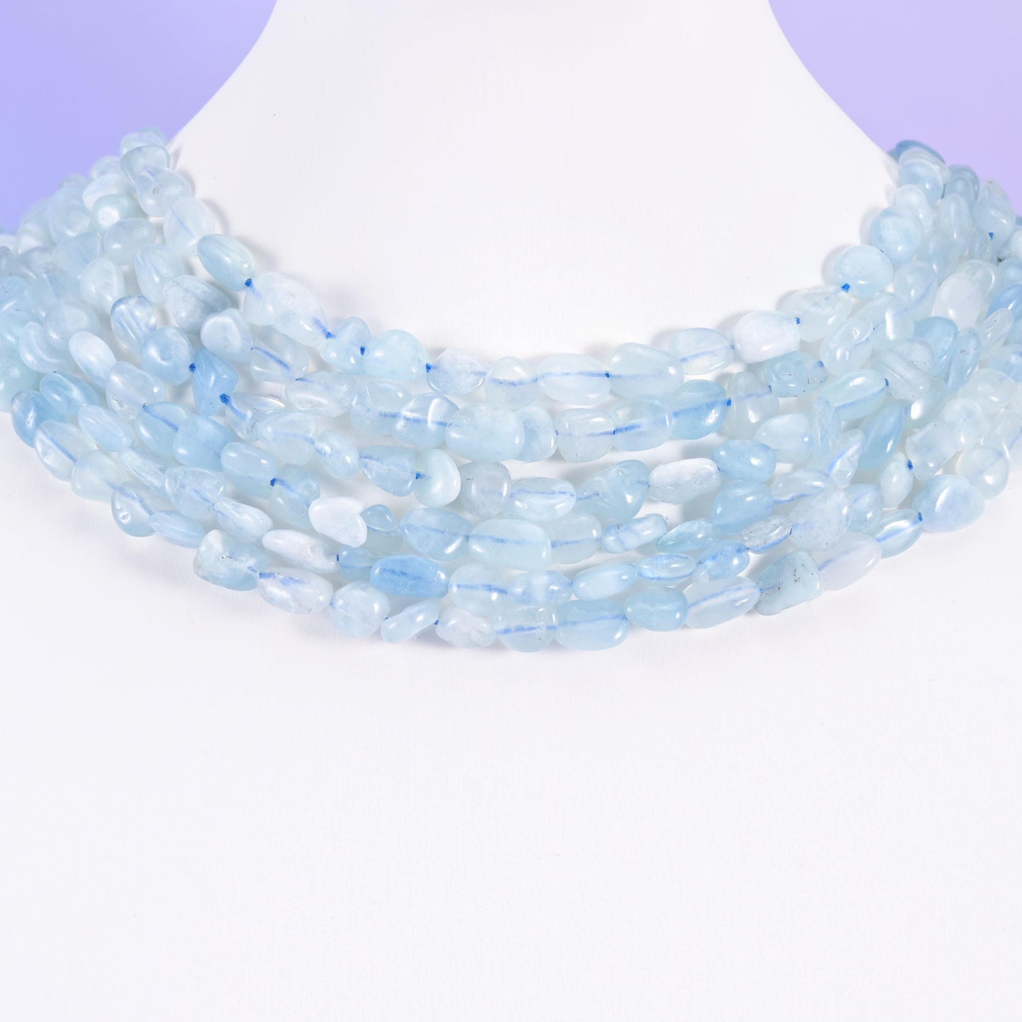 Aquamarine pebble nugget strands on a white display bust, worn as a layered collar