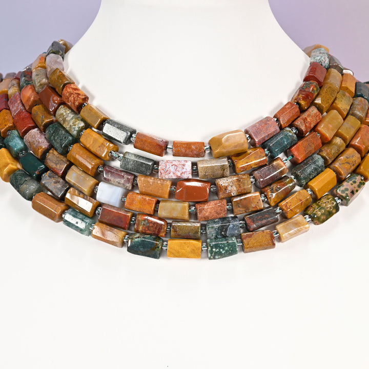 Multi-strand Ocean Jasper faceted tube bead necklace laid flat on a mannequin neck form against a lavender background.