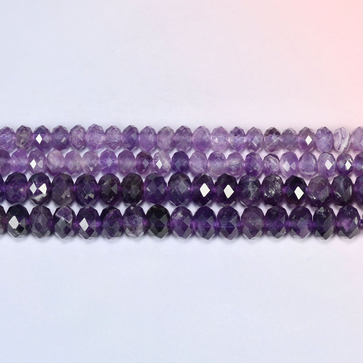 Purple amethyst faceted rondelle beads laid out in straight horizontal rows on a plain background, showing the even rondelle shape and bead size