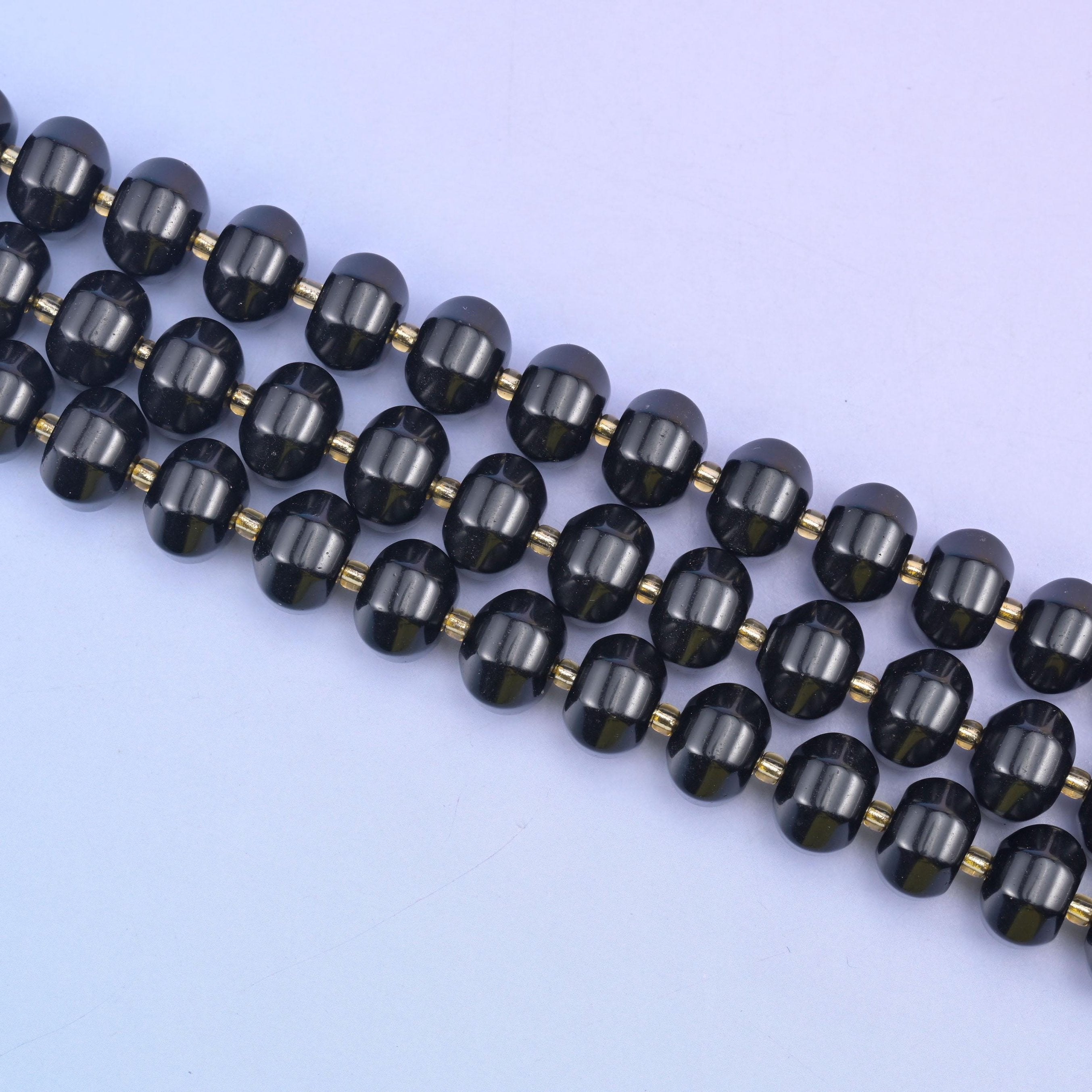 Angled run of 12x8mm obsidian pumpkin rondelles across pale lilac, gold seed beads between each stone