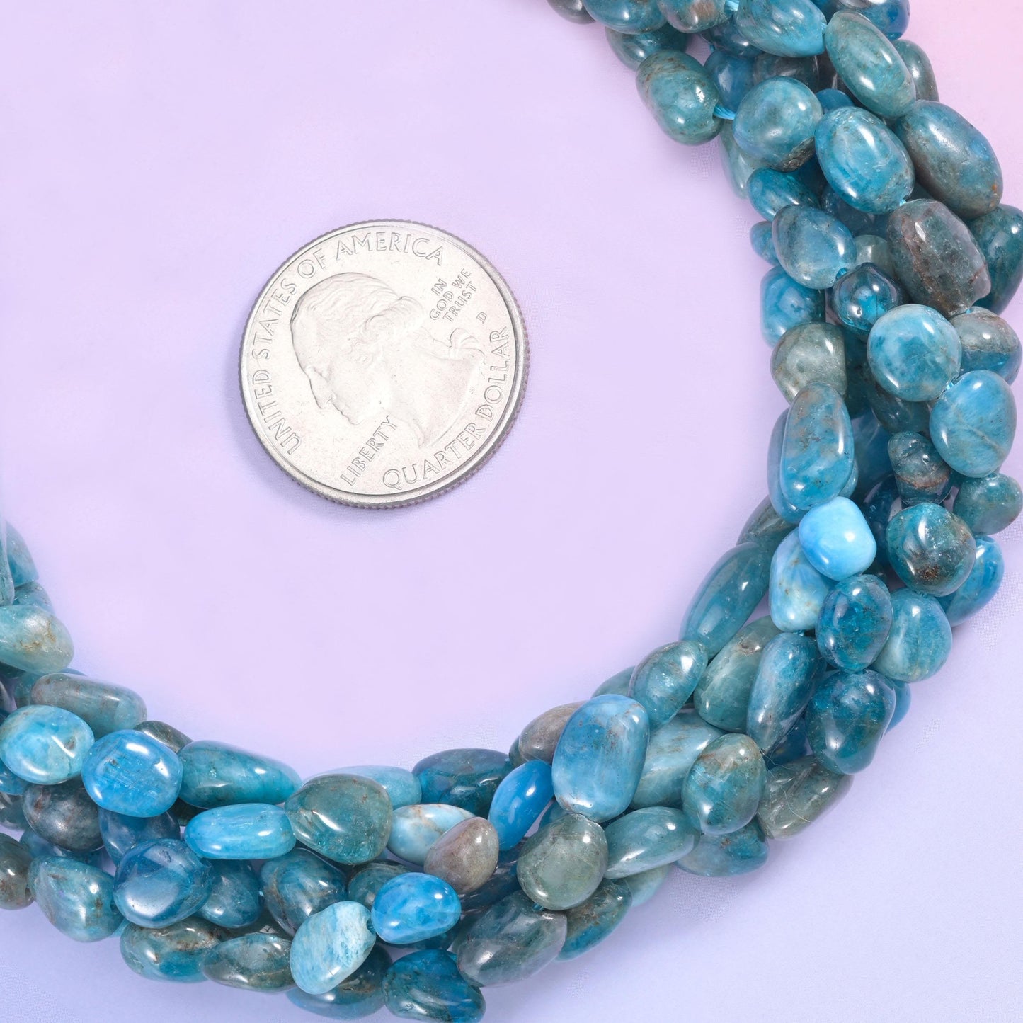 Teal and denim blue tumbled into smooth freeform pebbles, semi-translucent in places and streaked with grey-green and darker slate, so the strand looks like a handful of sea-worn stones.