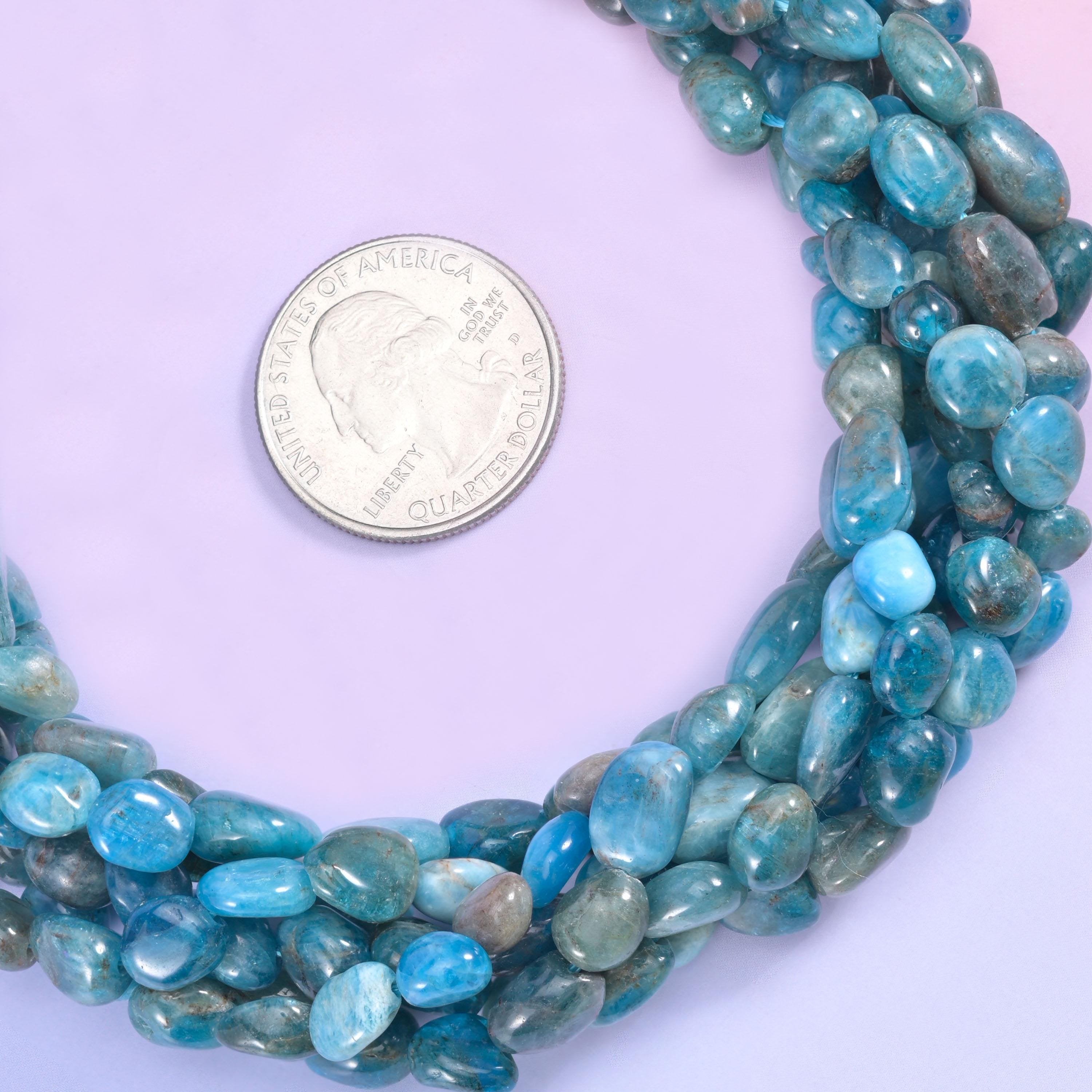 Teal and denim blue tumbled into smooth freeform pebbles, semi-translucent in places and streaked with grey-green and darker slate, so the strand looks like a handful of sea-worn stones.
