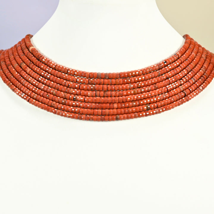 Red jasper faceted heishi disc strands arranged as a layered collar on a white display bust, brick red beads across the neck