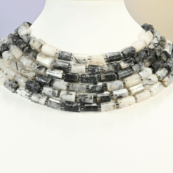 Black rutilated quartz faceted tube strands arranged as a layered collar on a white display bust, white and black beads across the neck