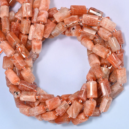 Rows of faceted Golden Strawberry Quartz tube beads laid straight on a lavender surface, showing the range of natural golden and coral coloring.
